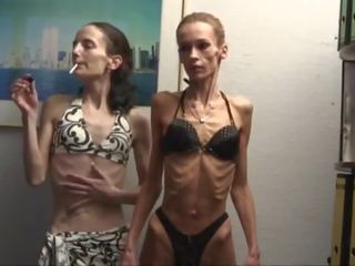 Anorektyczny dziewczyny poza w kąpielówki i rozciągać na the aparat fotograficzny
